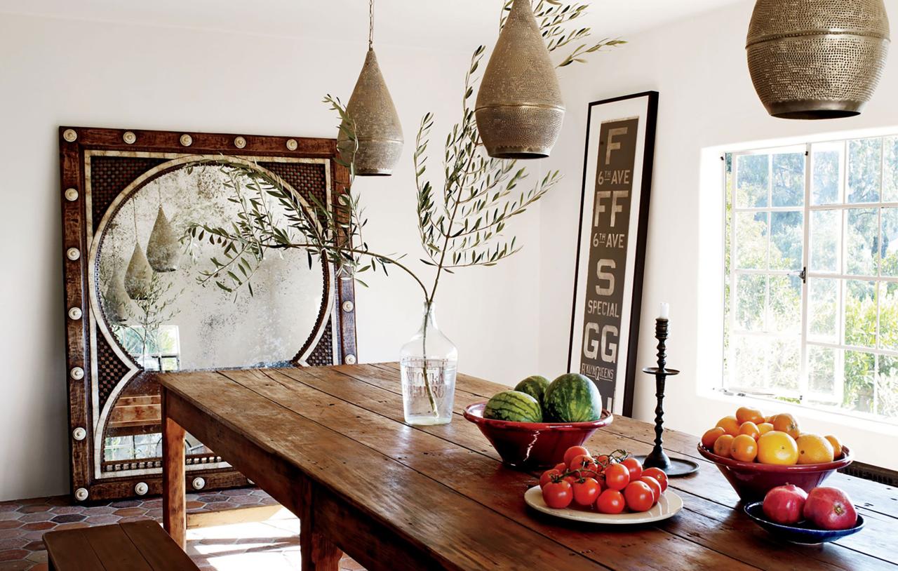 in the dining room lanterns are suspended above an antique guatemalan farmhouse table from dos gallo the mirror is by martyn lawrence bullard and the subway sign is vintage