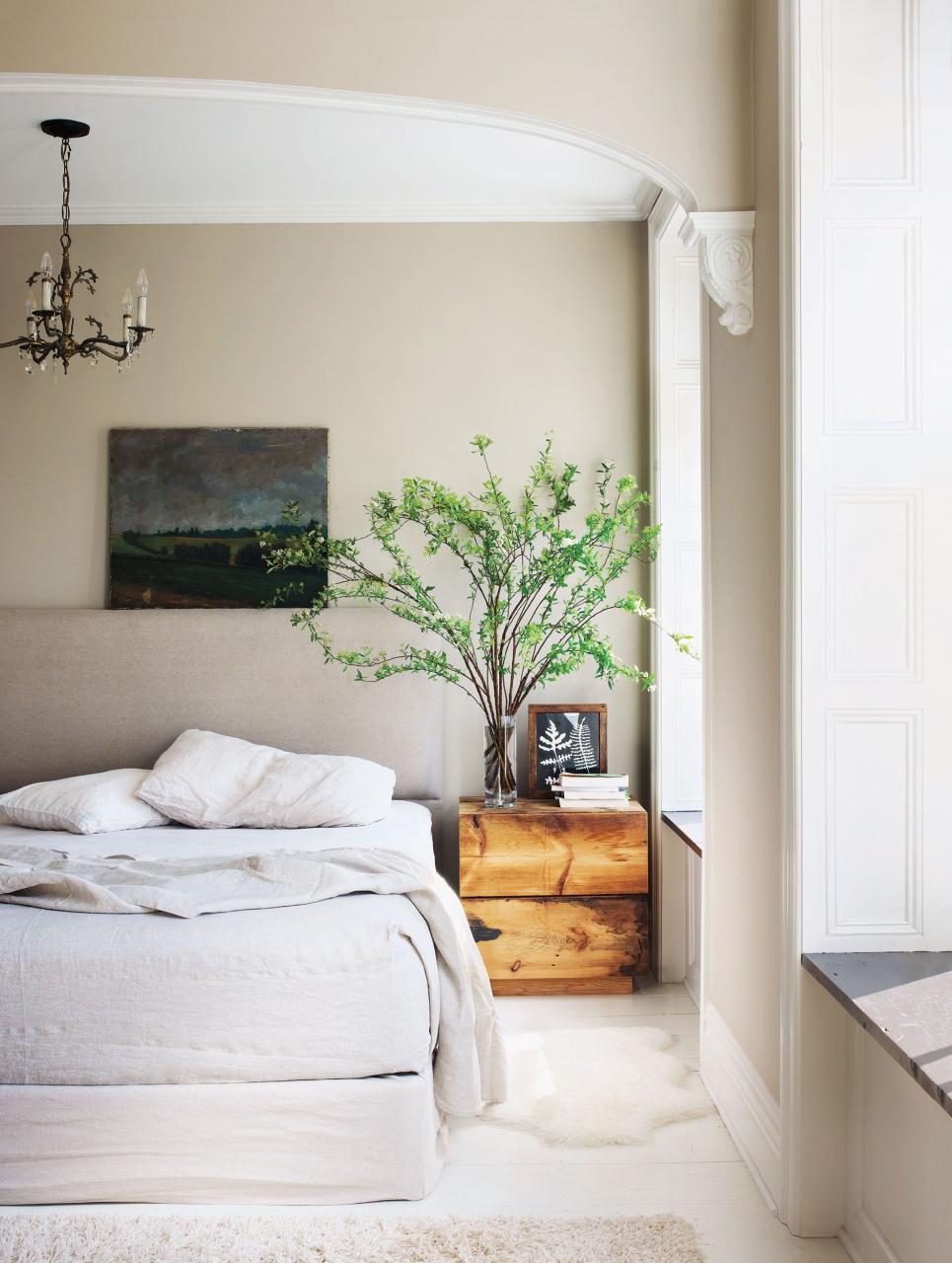 in the master bedroom the headboard fabric and bedding are by matteo the sheepskin rug is by ikea and the chandelier is an antiques fair find deary made the bedside table and the walls are painted in benjamin moores stone hearth