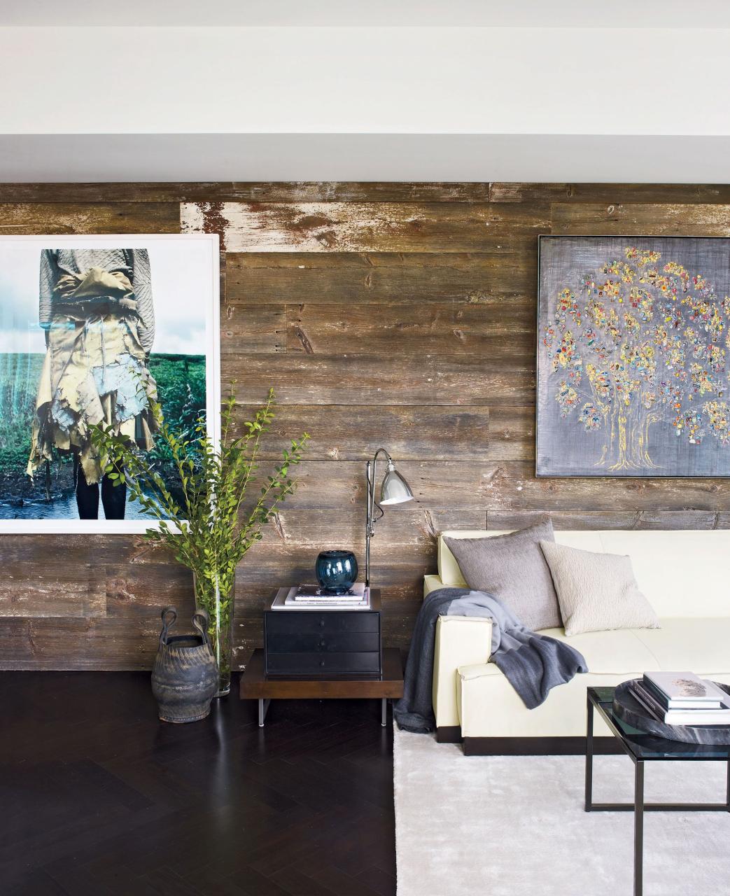 a wall in the living area is clad with planks of reclaimed barn wood the photograph is by jackie nickerson and the painting is by carlos vega