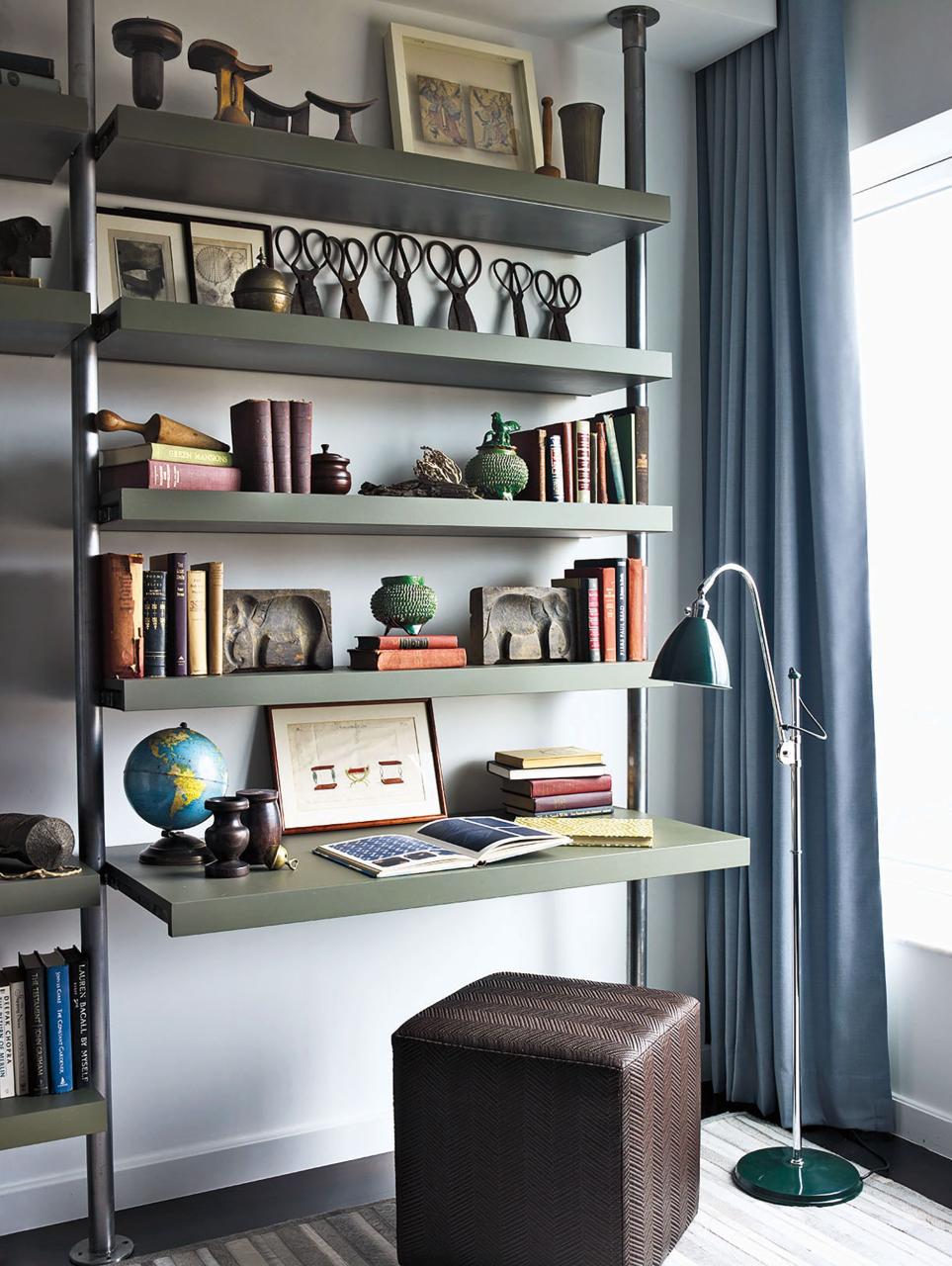 a floor lamp from design within reach stands next to custom made metal and wood shelving the ottoman is by calvin klein home