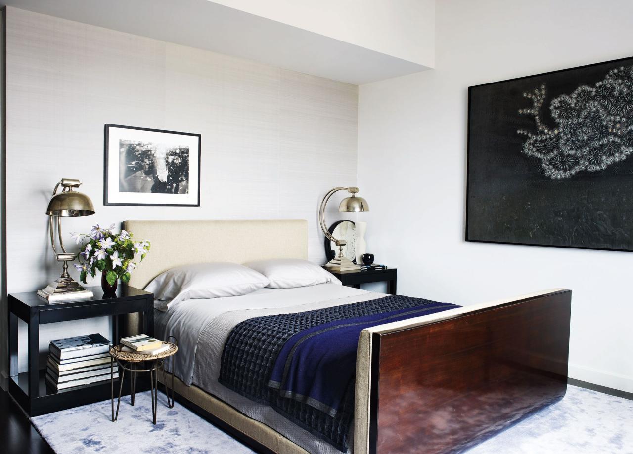 a wall of the master bedroom is covered in a silk by mdc wallcoverings and the bed bedding bedside tables and rug are by calvin klein home the side table and lamps are vintage and the painting is by carlos vega