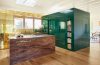 green lacquered cube hold appliances next to an island in pink marble