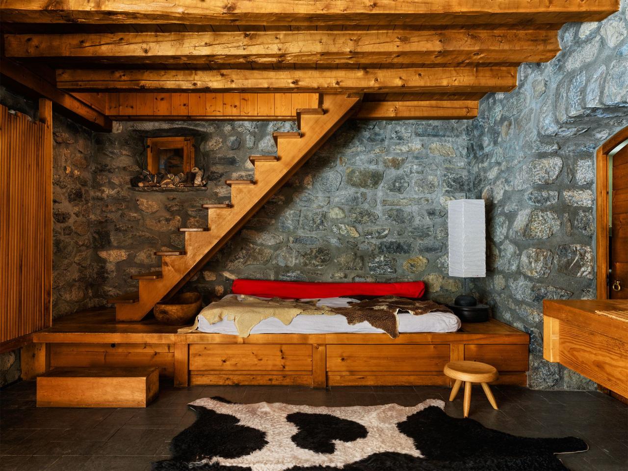 all wood panel daybed with stone walls and staircase leadin guyp and a faux cow rug