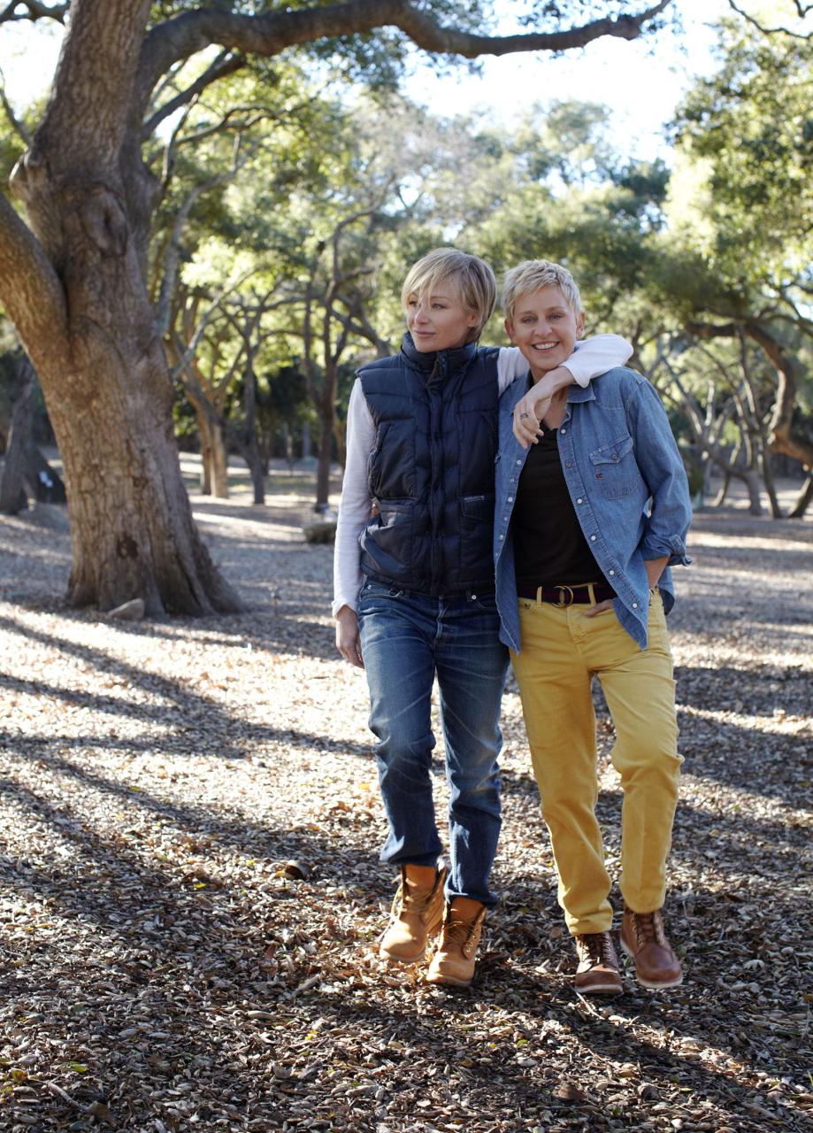 portia de rossi in jeans and a vest and work boot with arm around ellen degeneres in yellow pants and denim shirt and work boots outside