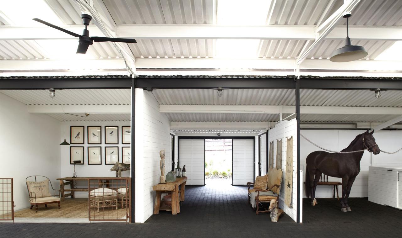 horse barn divided into three large rooms one with a horse and the other two with rustic furniture and sliding barn doors