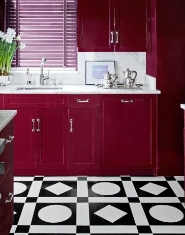 kitchen with red cherry cabinets and white marble counters and black and white geometric floor