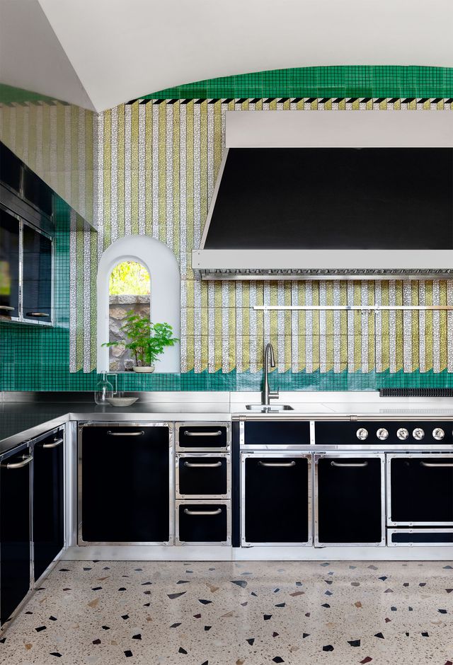 kitchen with speckled floor and green tiled wall behind counter