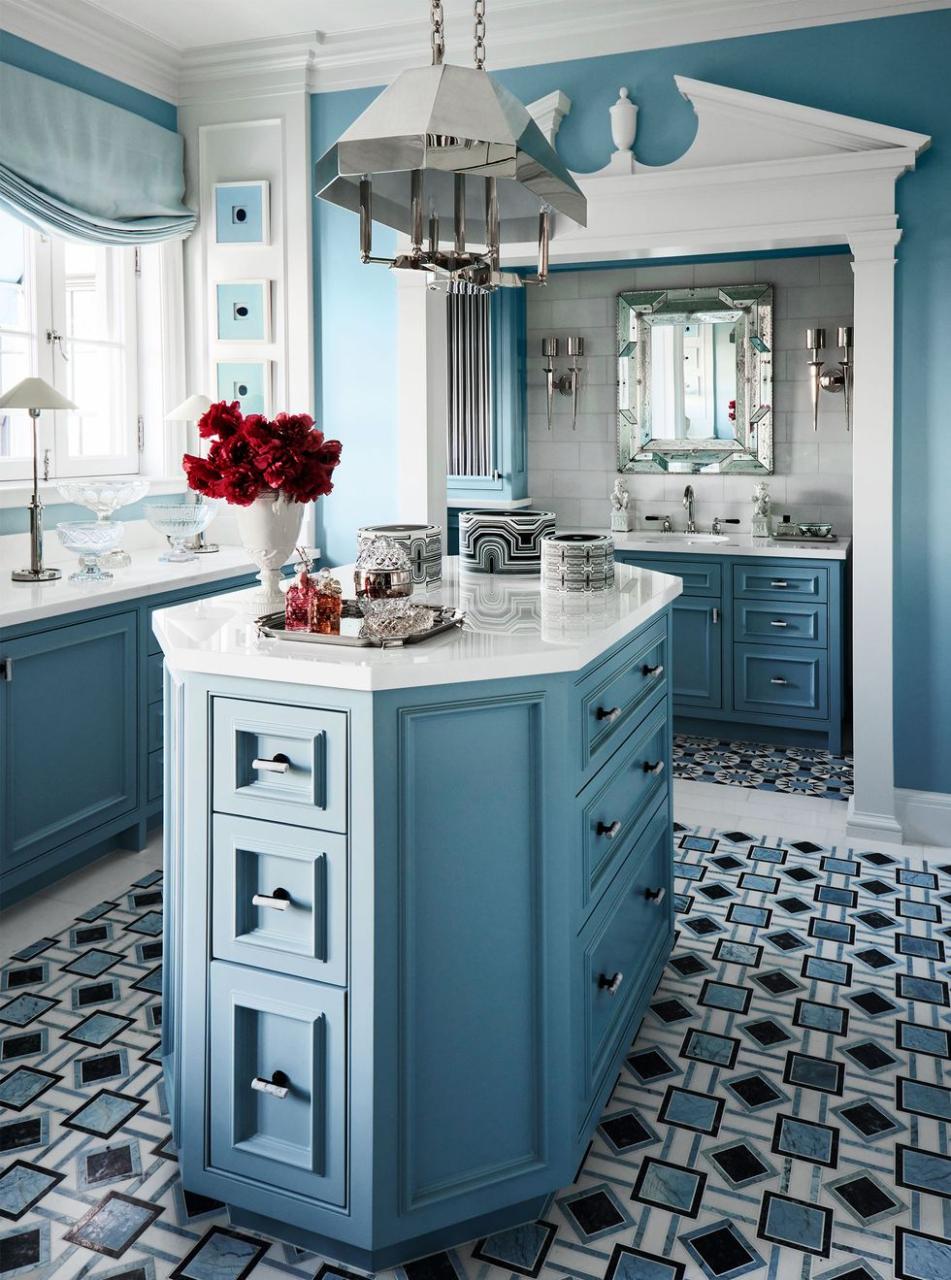 in a dressing room with blue walls and white trim is an octagonal island with multiple drawers and an octagonal pendant above, a sink and side counter with cabinets, square and diamond patterned floor