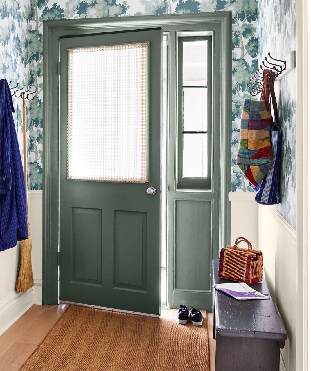 cozy entry with painted door with half window with white curtains and a bench and hooks on the right