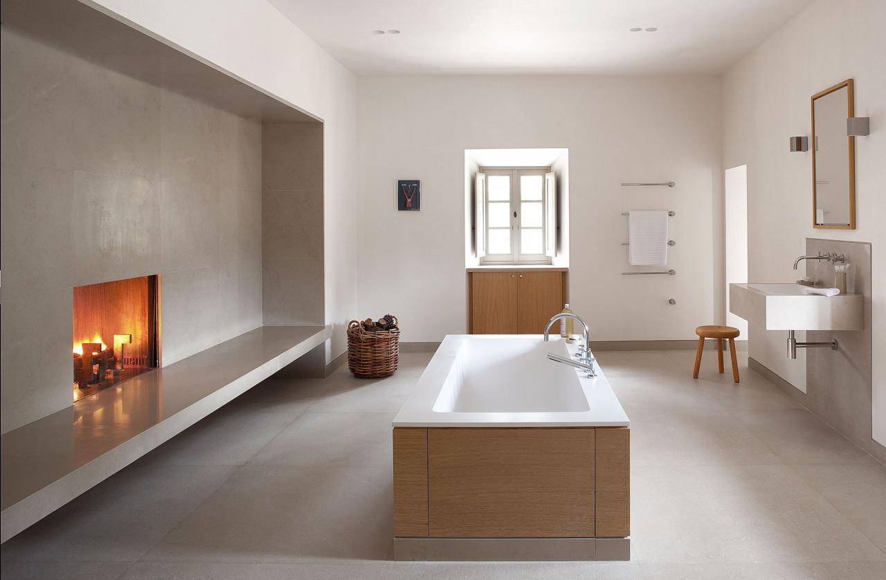 a large spare bathroom with tub at center and a cozy fireplace