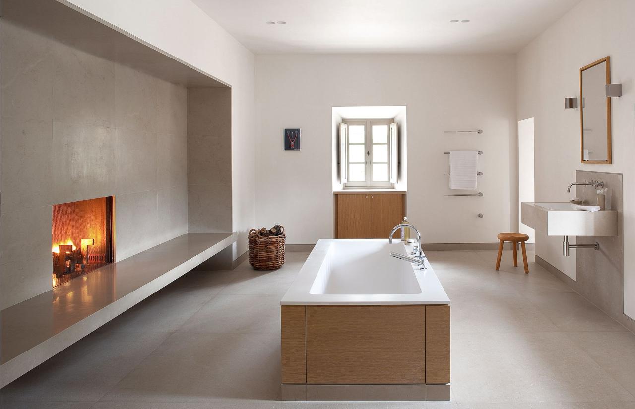 a large spare bathroom with tub at center and a cozy fireplace