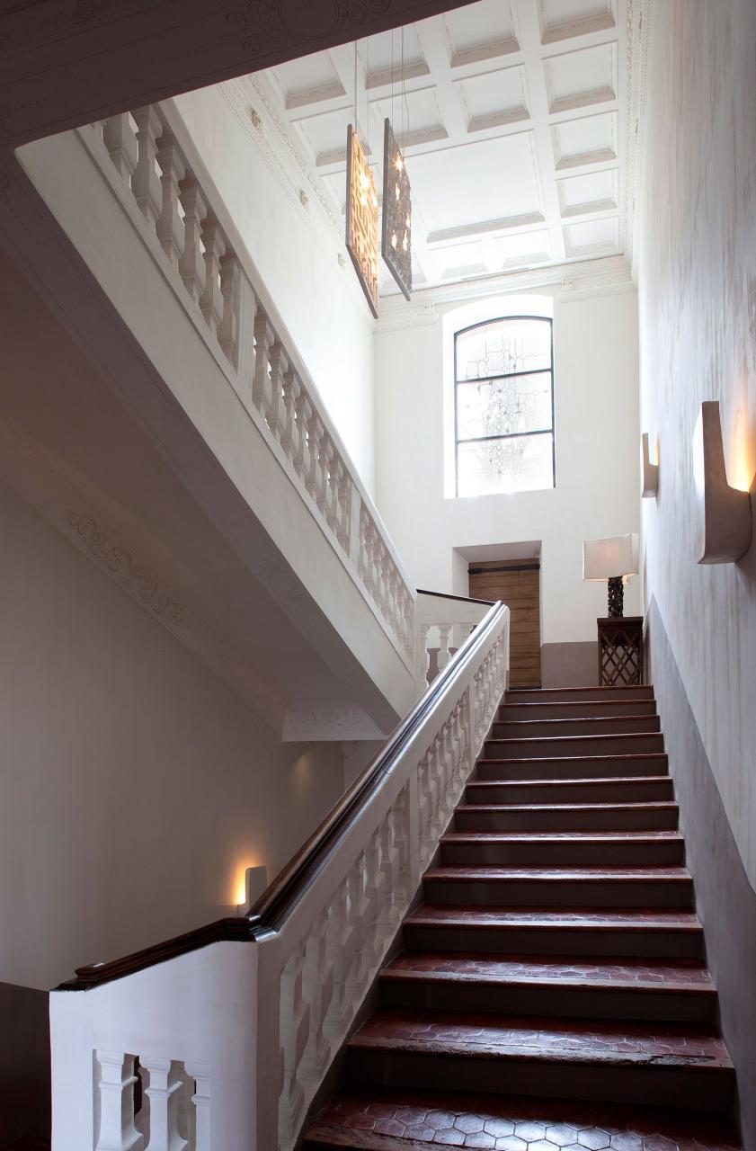 white staircase with wood topped banister and dark tiled steps