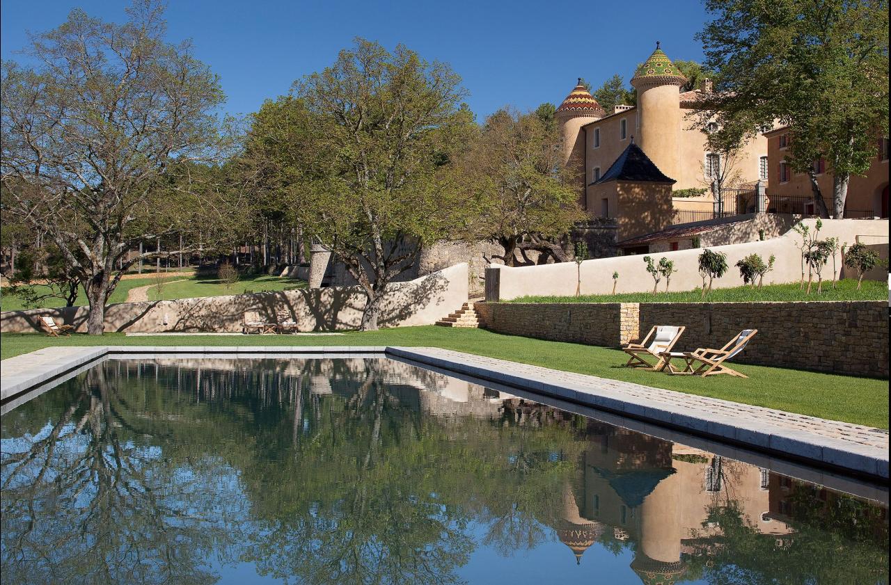 exterior of chateau with a large pool and grounds and stone walls