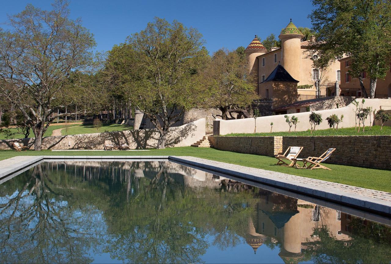 exterior of chateau with a large pool and grounds and stone walls