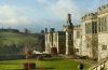 a large english manor building made of stone with a extensive lawn in front of it