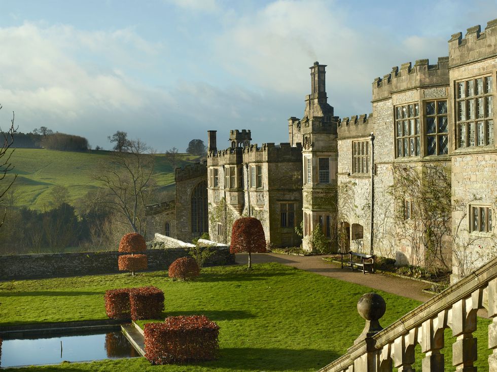 a large english manor building made of stone with a extensive lawn in front of it