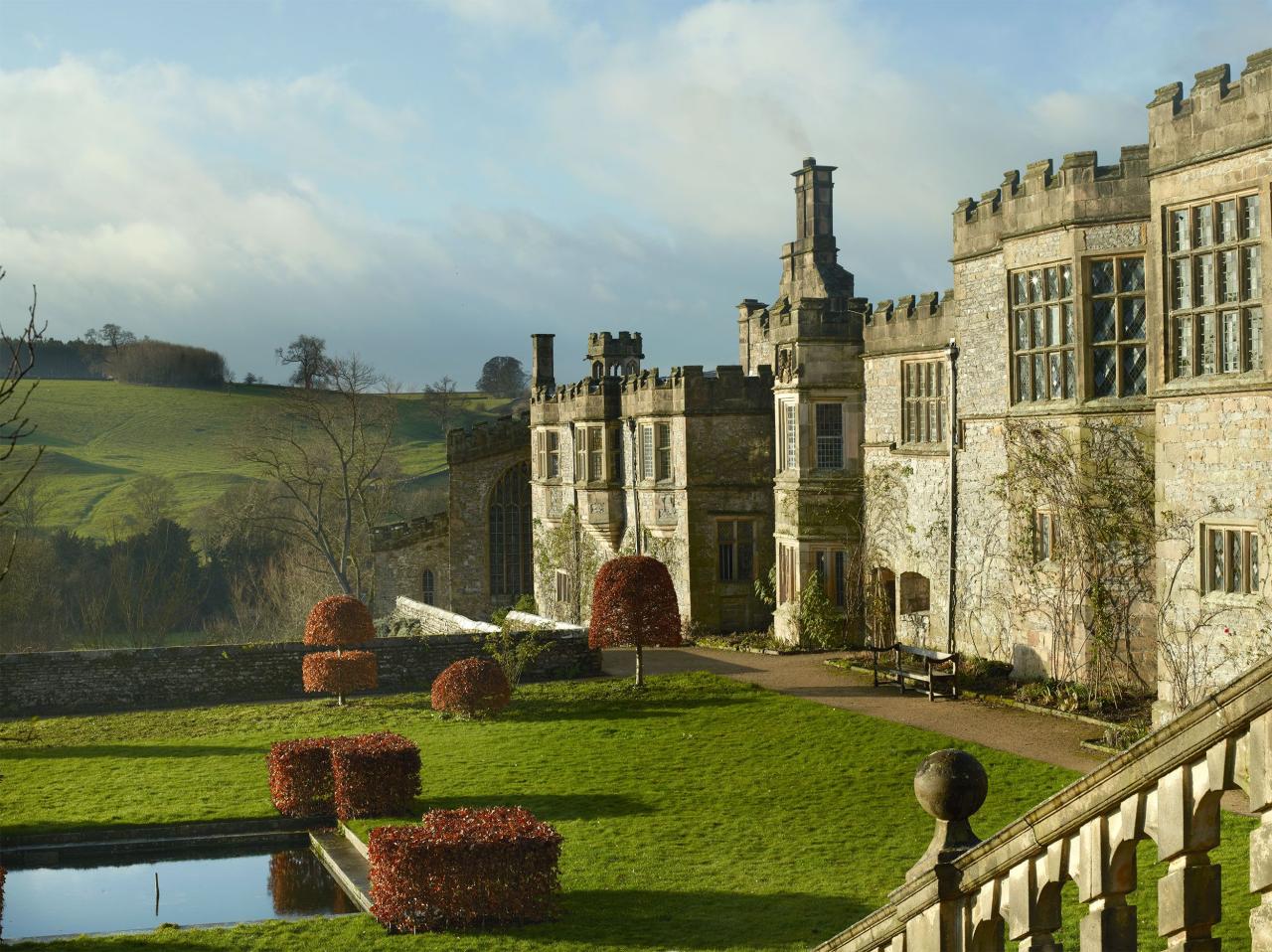 a large english manor building made of stone with a extensive lawn in front of it