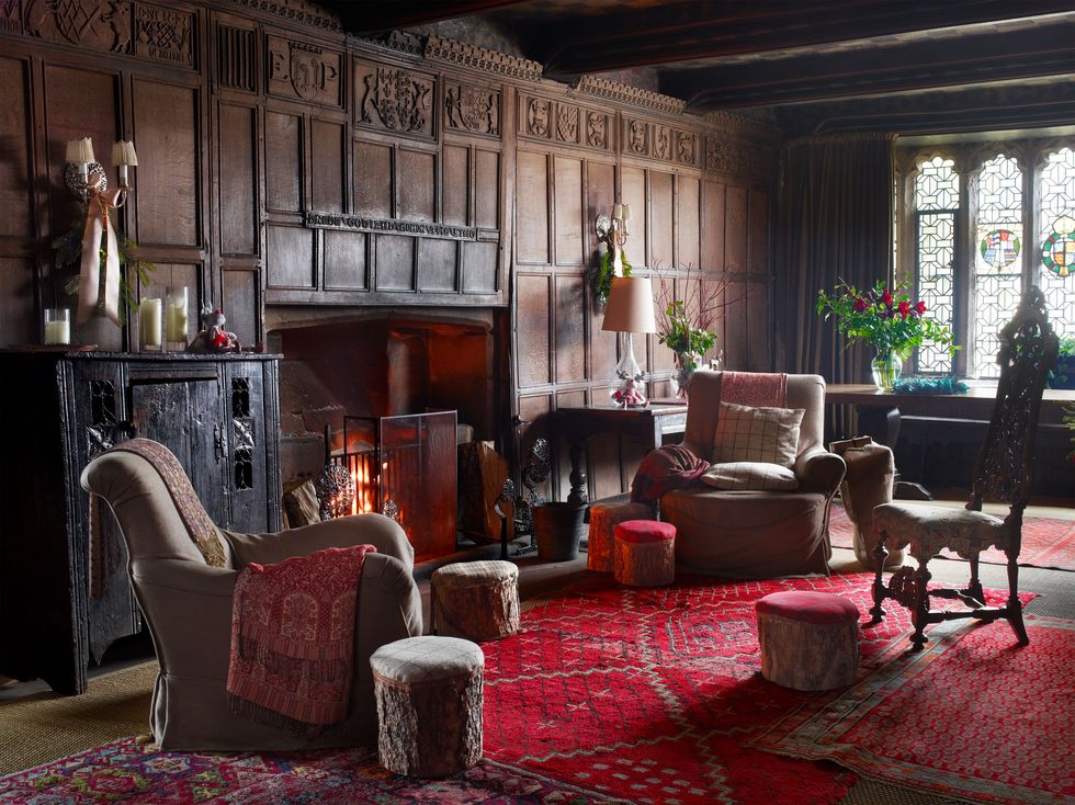 a paneled living room with red carpeting and plush armchairs and a fireplace