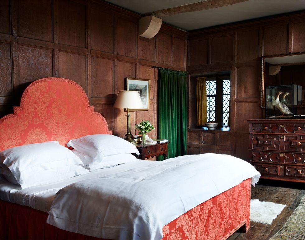 a panelled bedroom with a large bed with red headboard