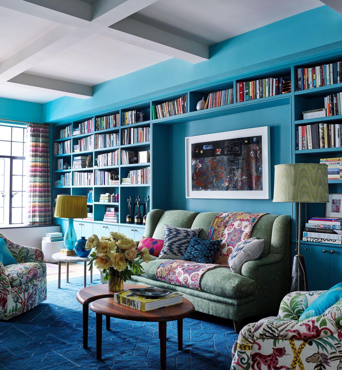 blue painted room with built in shelves with books and comfy sofas and chairs in muted florals and soft colors